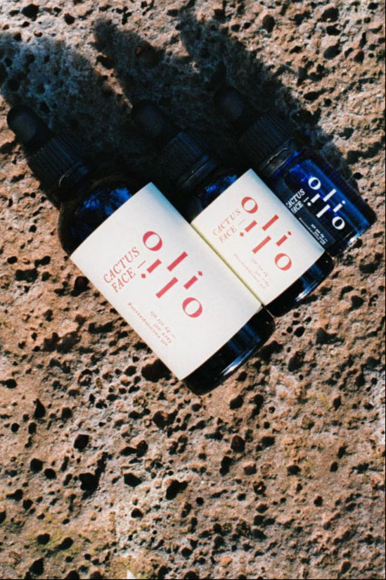 Three bottles of by oli oli cactus face on a textured stone surface